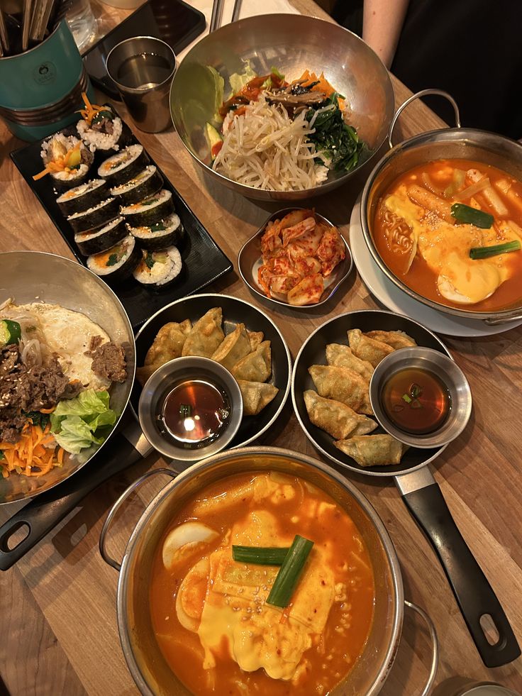 Bowls of Korean food including kimchi, soup, and rice on a wooden table